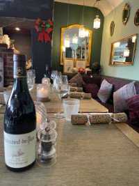 A wooden table featuring a bottle of wine alongside a glass, suggesting a cozy setting for relaxation or celebration